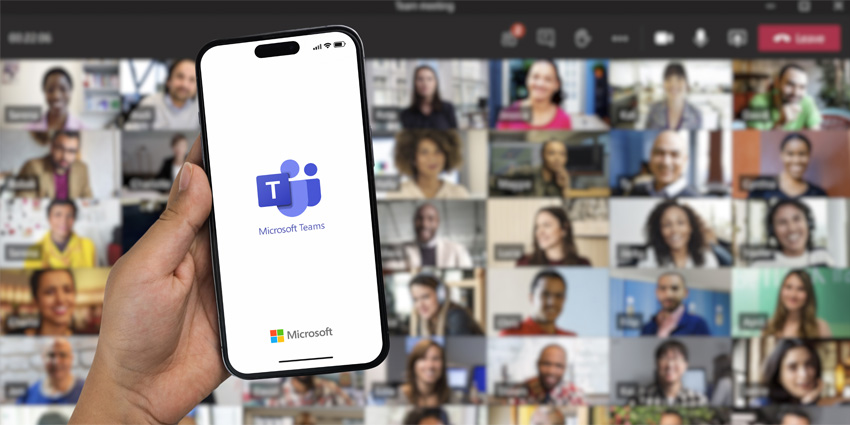 Boy holding a smartphone iPhone 14 Pro with Microsoft Teams app on the screen. Online meeting participants blurred in the background.